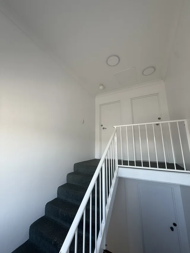 The same stairwell landing repainted in a clean, bright white