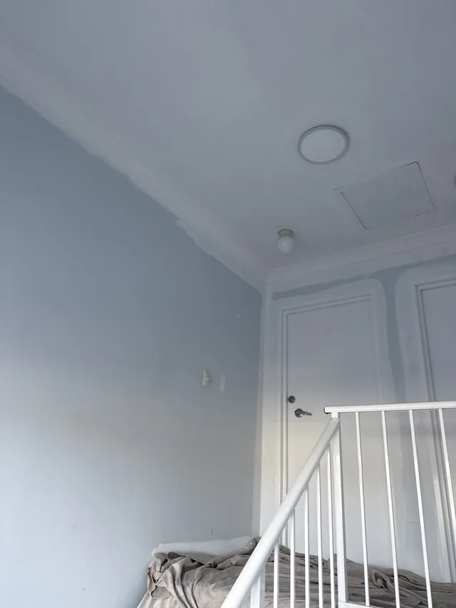 Interior stairwell landing with dull blue-grey walls before repainting