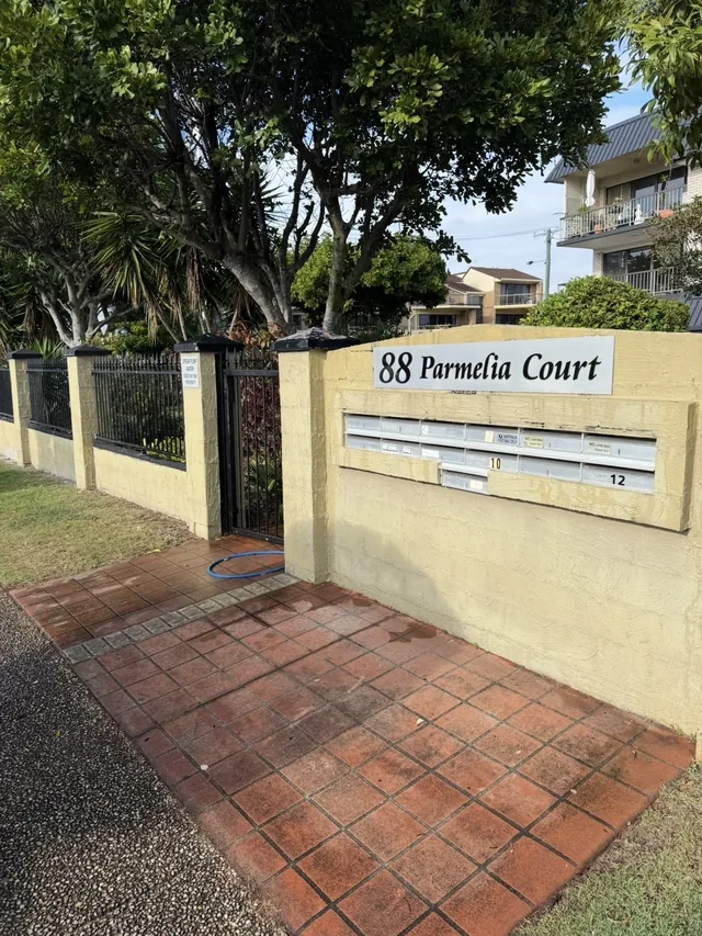 Body corporate boundary wall and letterbox surround in faded cream render before repainting